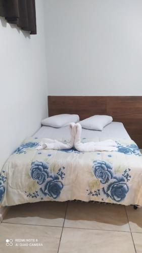 uma cama com lençóis e almofadas azuis e brancos em Pousada Quarto com tv,ar,frigobar,wifi e garagem em Aparecida