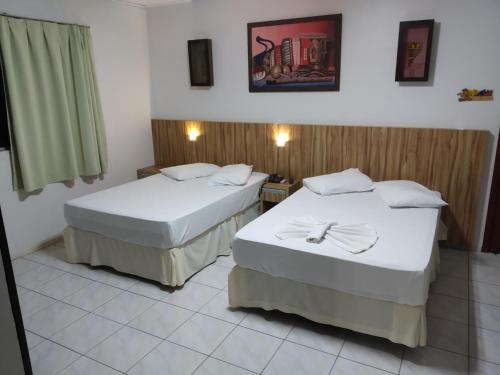 two beds in a hotel room with white sheets at Hotel Iguaçu in Dionísio Cerqueira