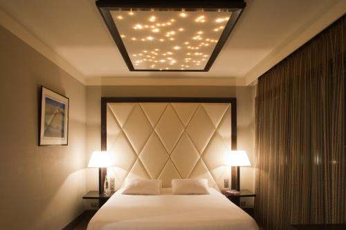 a bedroom with a bed with two lights above it at Le Safari Hotel Restaurant in Carpentras
