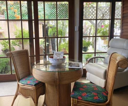 een glazen tafel en stoelen in een kamer met ramen bij Bongaree Ocean Villa in Bongaree