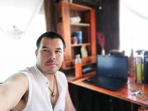 un hombre sentado frente a un escritorio con un portátil en Sustainable Cabain en Cozumel