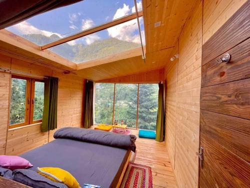 a room with two beds and a large window at Stargazing Cottages Jibhi in Jibhi