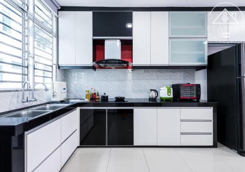 a kitchen with white cabinets and black counter tops at Port Dickson 14Pax 4BR Double Storey House in Port Dickson