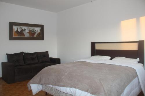 a bedroom with a large bed and a couch at Mais Incrível Localização de Gramado in Gramado