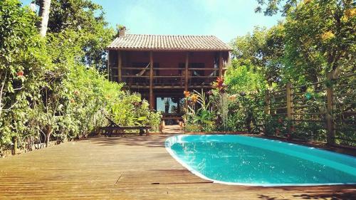 a house with a swimming pool next to a wooden deck at Casa de Temporada 4 Coqueiros, Piscina, 16 Hóspedes, 4 Suítes e Churrasqueira em Itacaré na Bahia in Itacaré