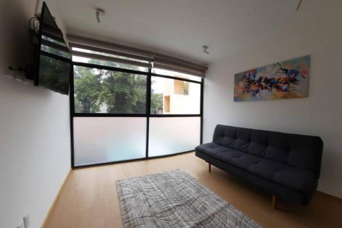 a living room with a couch and a large window at Increible Loft frente al WTC, Napoles in Mexico City