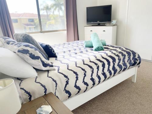 a bed with a blue and white comforter and a television at Cloud 8 on Welsby in Bongaree