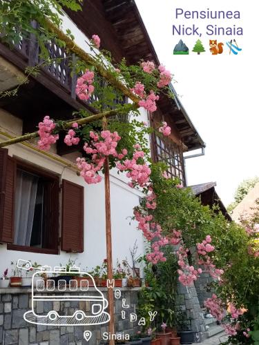 une maison avec des fleurs roses sur son côté dans l'établissement Pensiunea Nick, à Sinaia