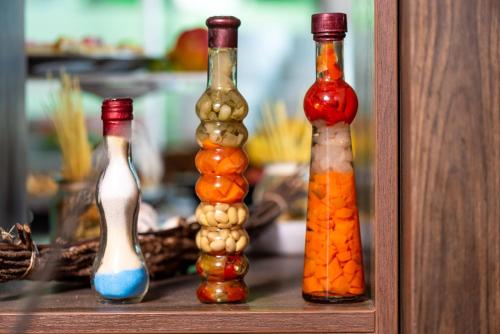 four glass bottles lined up on a shelf at Aparthotel Hotel Prestige City II in Primorsko