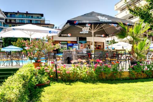 a restaurant with an umbrella and some chairs and flowers at Aparthotel Hotel Prestige City II in Primorsko