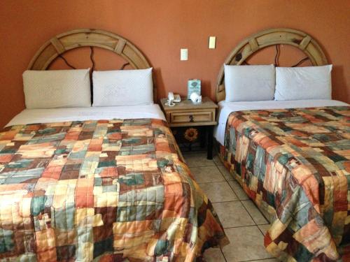 a hotel room with two beds and a night stand at Hotel La Paz in Guadalajara