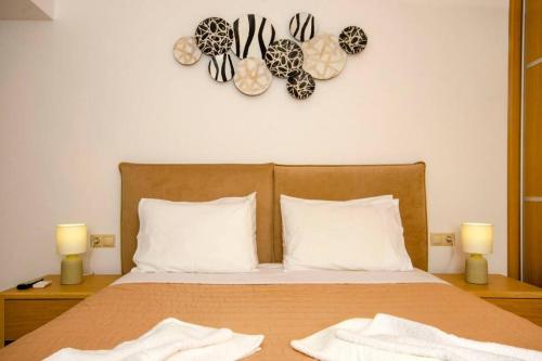 a bed with two white pillows and a clock on the wall at Mare Monte Luxury Apartment in Kissamos