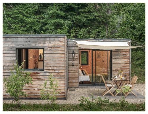 a small wooden cabin with a table and a tent at Volvic Organic Resort in Volvic