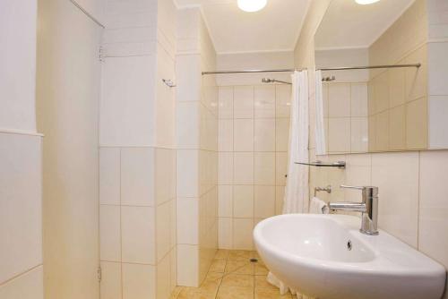 Un baño blanco con lavabo y ducha. en Econo Lodge Portland, en Portland