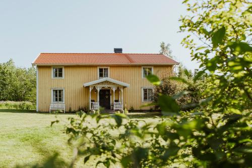 uma velha casa amarela com um telhado vermelho em Kylås Vildmark em Skillingaryd