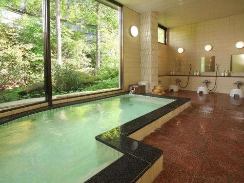 a swimming pool in a bathroom with a large window at Kimimachisou in Chino