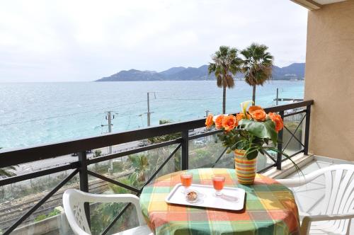 una mesa con un jarrón de flores en el balcón en Residhotel Villa Maupassant, en Cannes