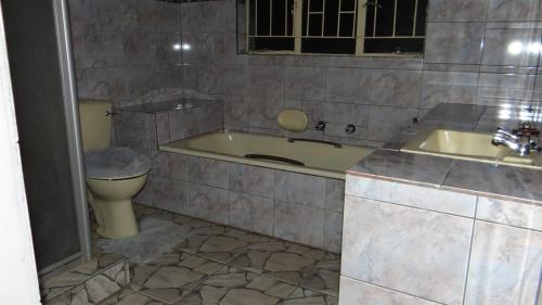 a bathroom with a tub and a toilet and a sink at Warmbaths Thai Spa and Guest House in Bela-Bela