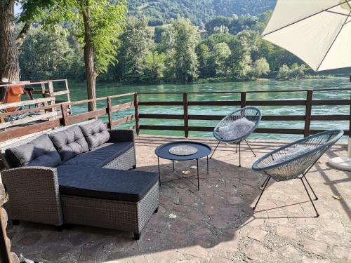 a patio with a couch and two chairs and an umbrella at Kutak na Drini in Ljubovija