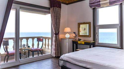 a bedroom with a bed and a balcony with the ocean at Pension Badawa in Gangneung