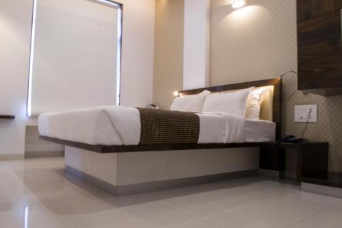 a bedroom with a large bed with white sheets and pillows at Hotel SRI SRI EXECUTIVE KOLHAPUR NEAR MAHALAXMI TEMPLE in Kolhapur