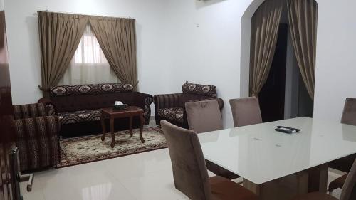 Orient Apartments في نزوى‎: غرفة معيشة مع طاولة وأريكة