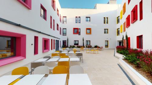 einen Innenhof mit Tischen und Stühlen in einem Gebäude in der Unterkunft Residencia Universitaria Málaga Centro in Málaga