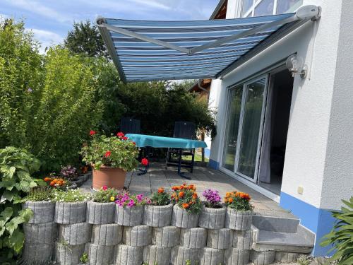 een blauwe luifel boven een patio met bloemen en een tafel bij Ferienwohnung - Haus Waibel in Überlingen