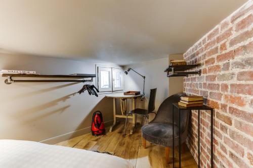 a room with a bed and a desk and a brick wall at Bail Mobilité Appartement, Place Vendome, Opera in Paris