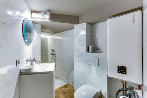 een witte badkamer met een wastafel en een spiegel bij Bail Mobilité Appartement, Place Vendome, Opera in Parijs