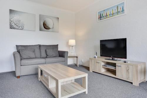 a living room with a couch and a flat screen tv at Ocean Drive Apartments in Merimbula