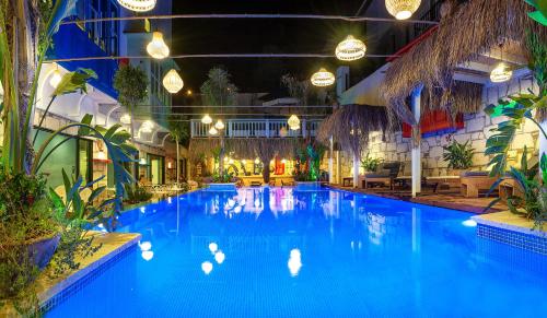 a large swimming pool with blue water at night at TNR Otel & Spa in Kusadası