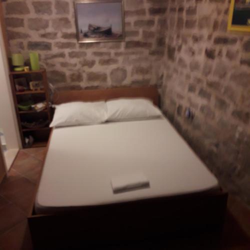 a bed in a room with a brick wall at room Ami in Kaštela