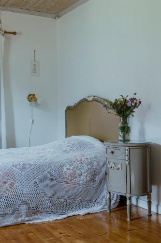 a bed with a table with a vase of flowers on it at Kylås Vildmark in Skillingaryd