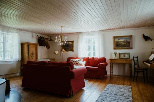 a living room with two red couches and a ceiling at Kylås Vildmark in Skillingaryd