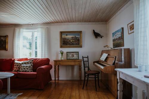a living room with a red couch and a piano at Kylås Vildmark in Skillingaryd