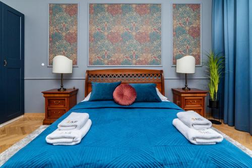 a bedroom with a blue bed with towels and two lamps at Trzy Gracje - Monte Cassino by OneApartments in Sopot