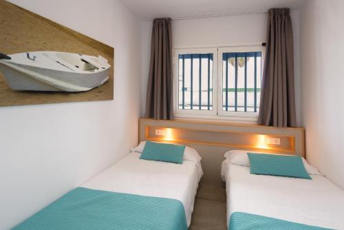 two beds in a room with a boat on the window at Apartamentos Playamar in Puerto del Carmen