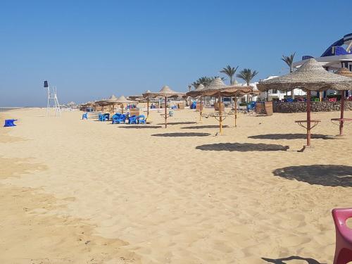 a sandy beach with umbrellas and chairs on it at Golden Beach 1 for family in Ras Sedr