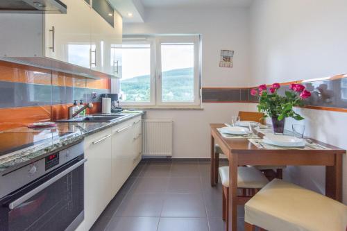 a kitchen with a wooden table and a table sidx sidx sidx at Apartamenty Izerskie - ul. Cicha 13F-G in Świeradów-Zdrój