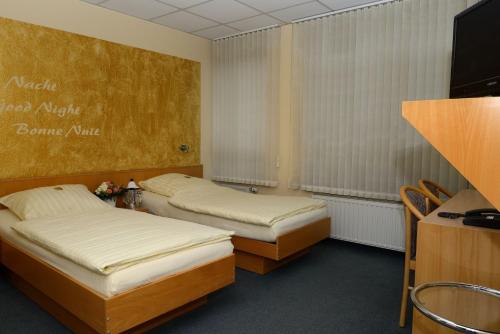 two beds in a room with a tv at Hotel Alberga in Mettmann