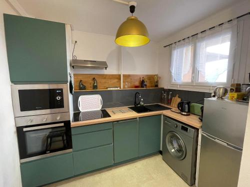 a kitchen with green cabinets and a washing machine at Turgot bleu in Thonon-les-Bains