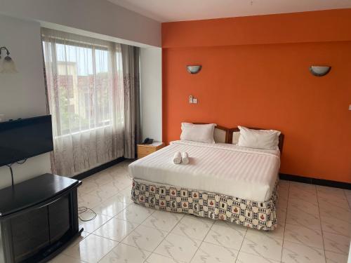a bedroom with a large bed with an orange wall at Panama Inn Moshi in Moshi