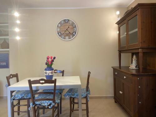 a dining room with a table and a clock on the wall at ISCA BLUE BEACH Casa in Villa vicino al mare, sino a max 8 persone in Isca sullo Ionio