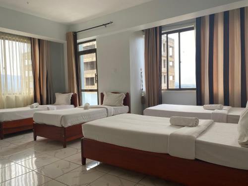 a hotel room with three beds and two windows at Panama Inn Moshi in Moshi
