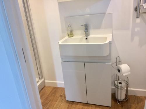 a white bathroom with a sink and a toilet paper roll at The Citiroom in Chichester