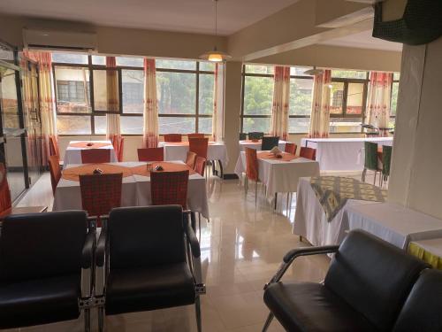 a dining room with tables and chairs and windows at Panama Inn Moshi in Moshi