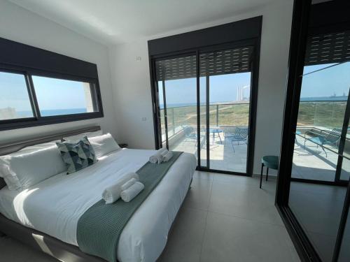 a bedroom with a large bed with a view of the ocean at #דירת יוקרה על הים Seabreeze Beach Apartment# in Giv‘at Olga