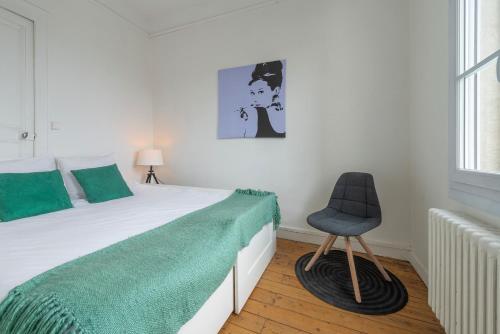 une chambre avec un lit et une chaise dedans dans l'établissement Appartement Coeur de Ville rue Saint-Laud, à Angers
