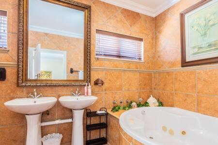 a bathroom with two sinks and a tub and a mirror at La Posada Umhlanga in Durban